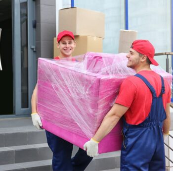 Zwei Umzugshelfer tragen ein in Folie gepacktes Möbelstück – Umzug in Michelstadt