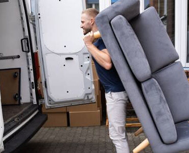 Möbellift Michelstadt Möbellift Michelstadt: Helfer tragen ein graues Sofa aus einem Transporter